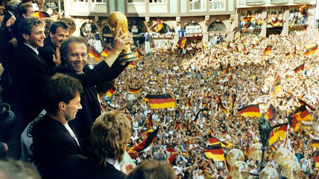 Bild: picture alliance / dpa | Kai-Uwe Wärner Viele tausend Menschen bereiten den Spielern der deutschen Fußball-Weltmeistermannschaft am 09.07.1990 auf dem Römerberg in Frankfurt am Main einen begeisterten Empfang mit viel Jubel und einem Meer an deutschen Fahnen.